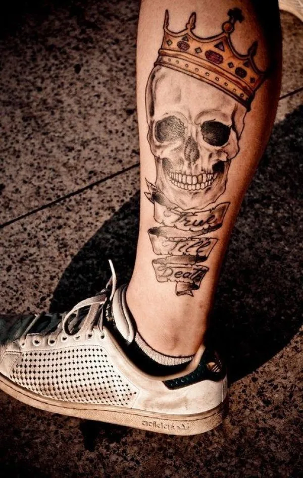 Skull having crown on his head inked on lower leg.