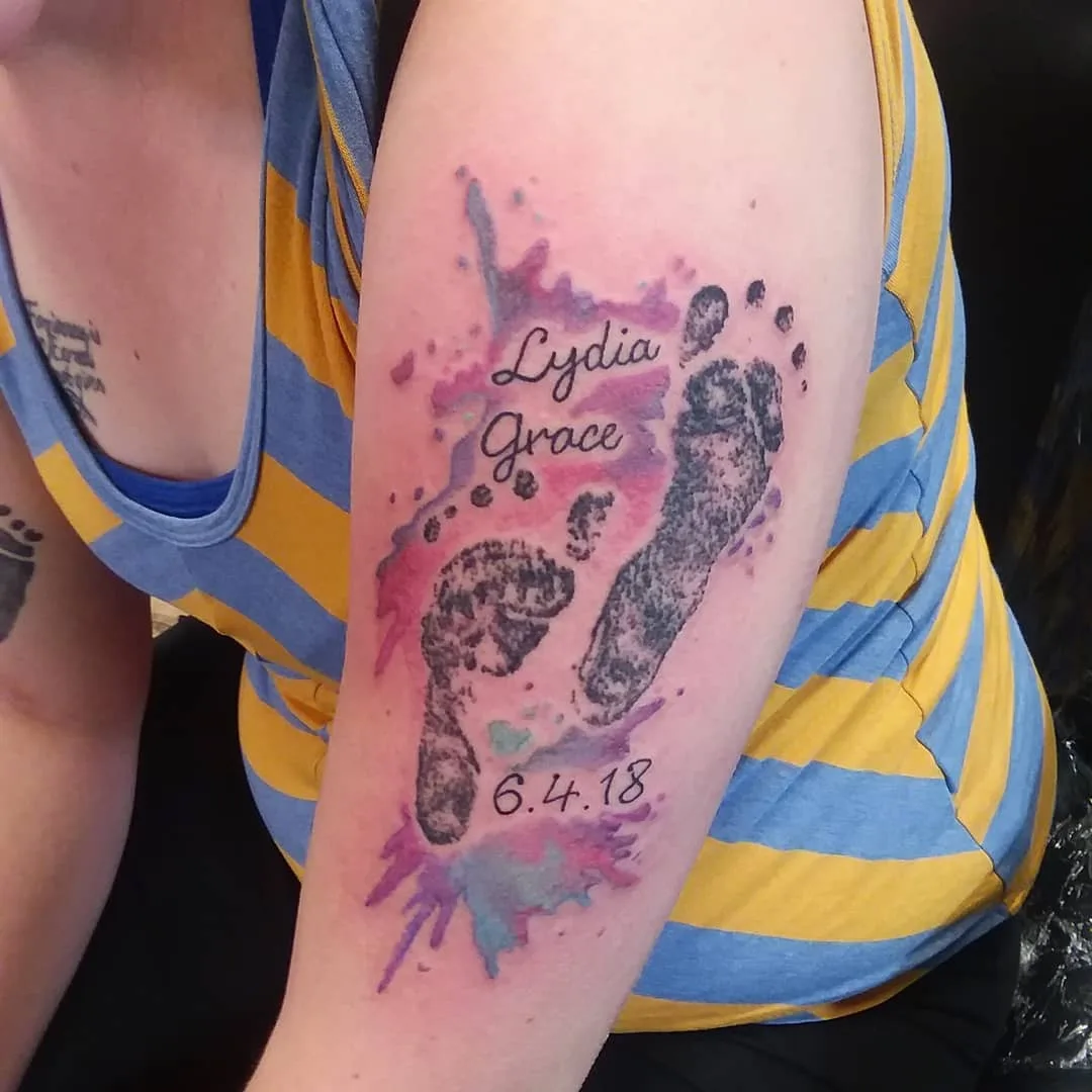 Swanky watercolor footprint tattoo on sleeve.