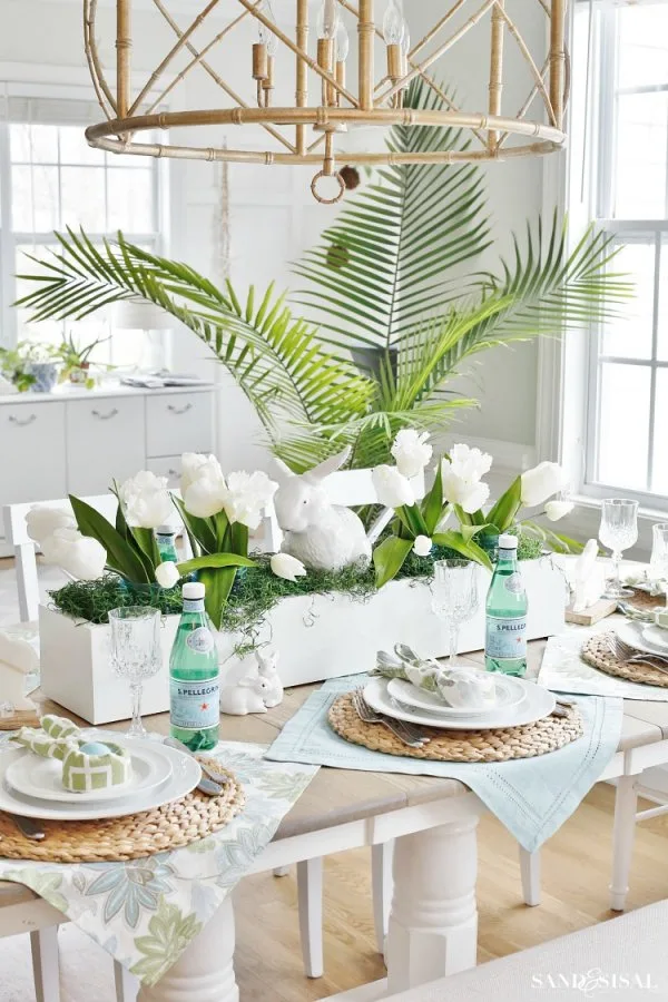 Festive tablescape with a DIY wood trough centerpiece filled with four blue mason jars, tulips, green Spanish moss, and a big ceramic bunny.