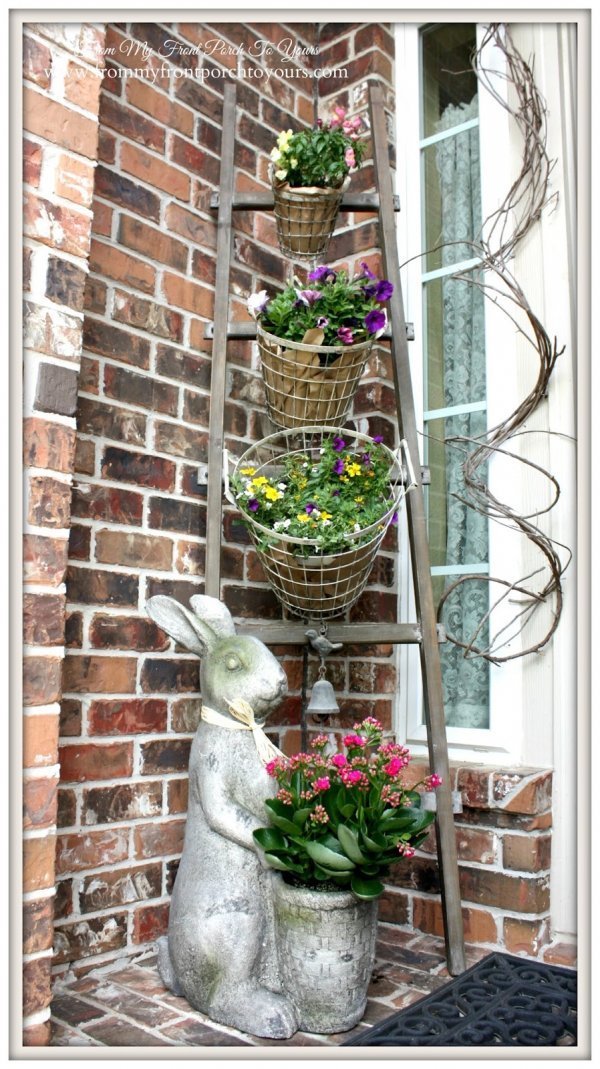 Antique white wire basket planters and ladder plant stand with bunny for Easter outdoor decor.