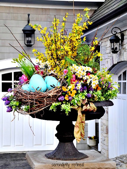 Beautiful spring urn with birds nest daffodils, tulips and forsythia.