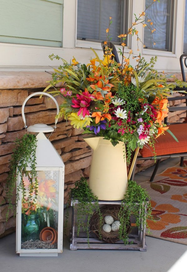 Lantern and watering can floral display for porch decor.